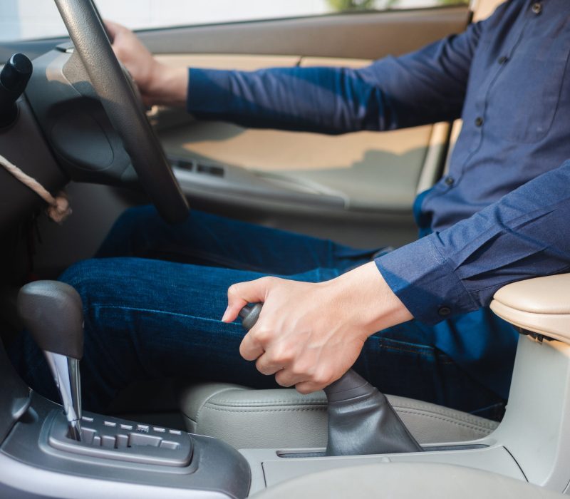 driver's hand pulling the hand brake in a car